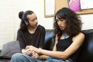 A genderqueer person comforting a transgender woman on a therapists couch - corregulación durante las reuniones - Sociocracy For All