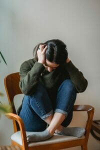 A person in an office chair holding their head, distressed.