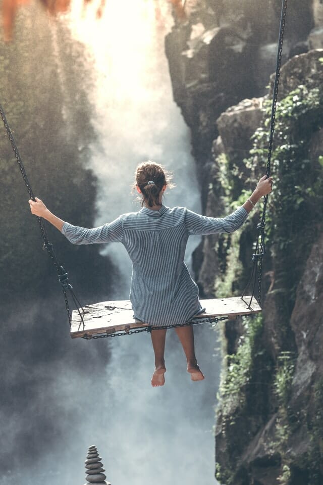 A picture of a person going on a swing on a not so safe edge of a cliff.