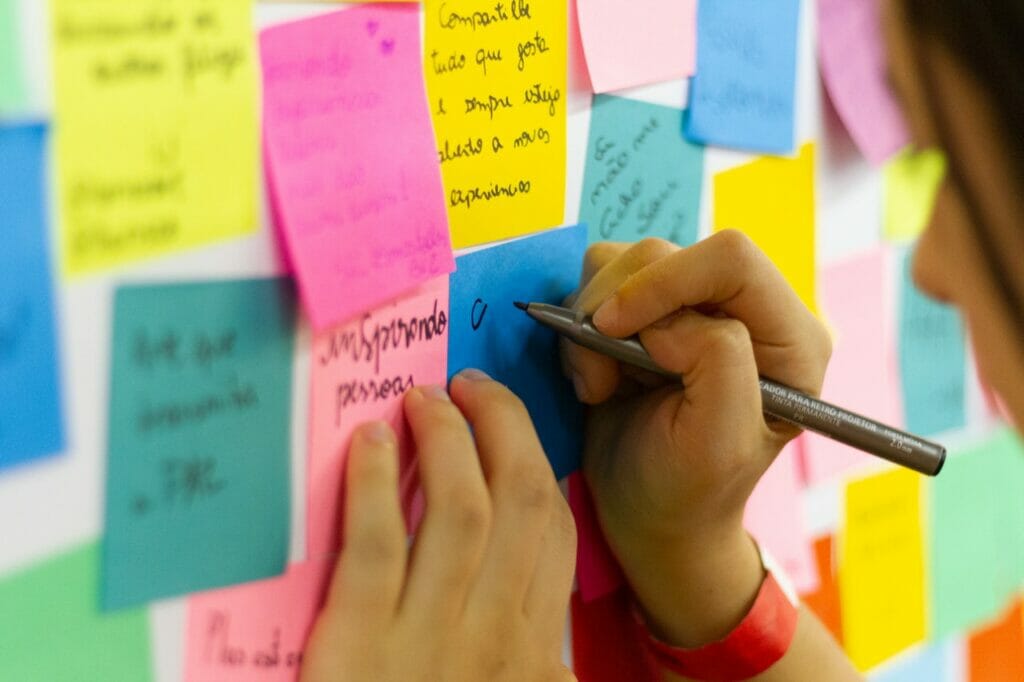 Picture of a person writing feedback on a post-it. It could be for performance reviews.