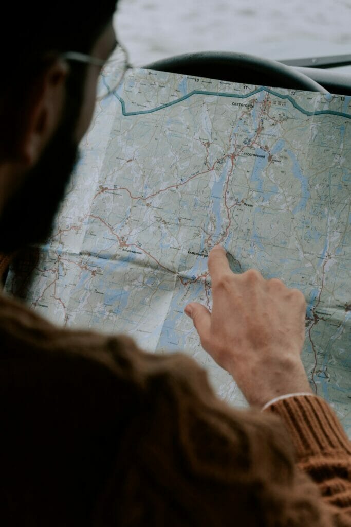 Person pointing at map in car.