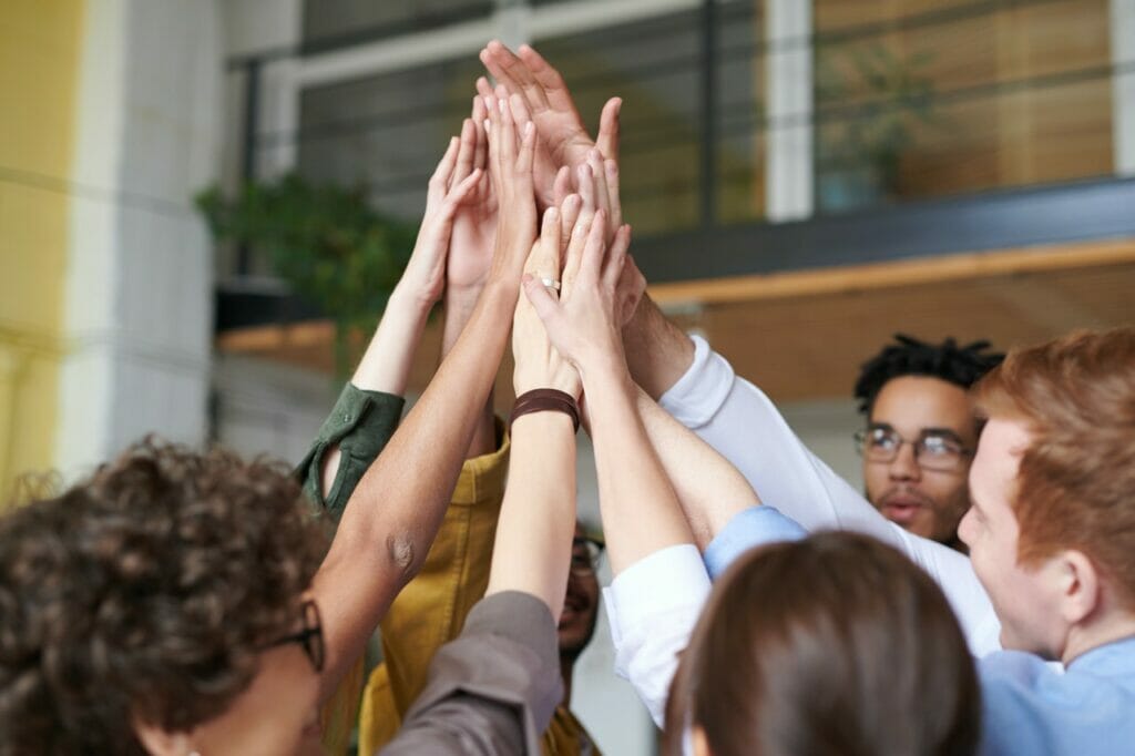 A group of people high-fiving after a meeting together.