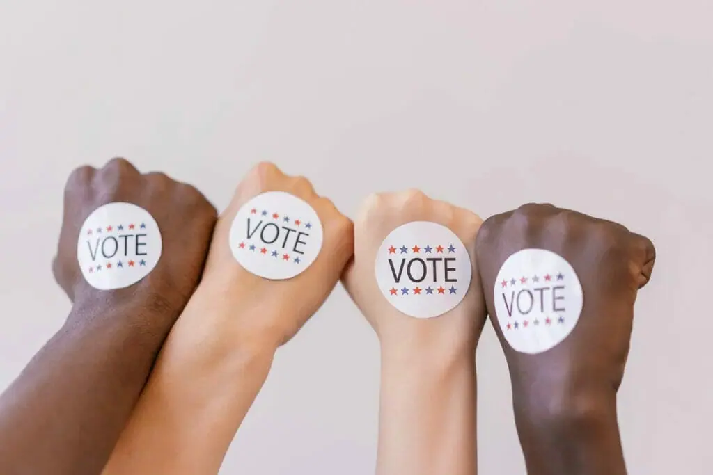 Hands raised in fists with "vote" stickers